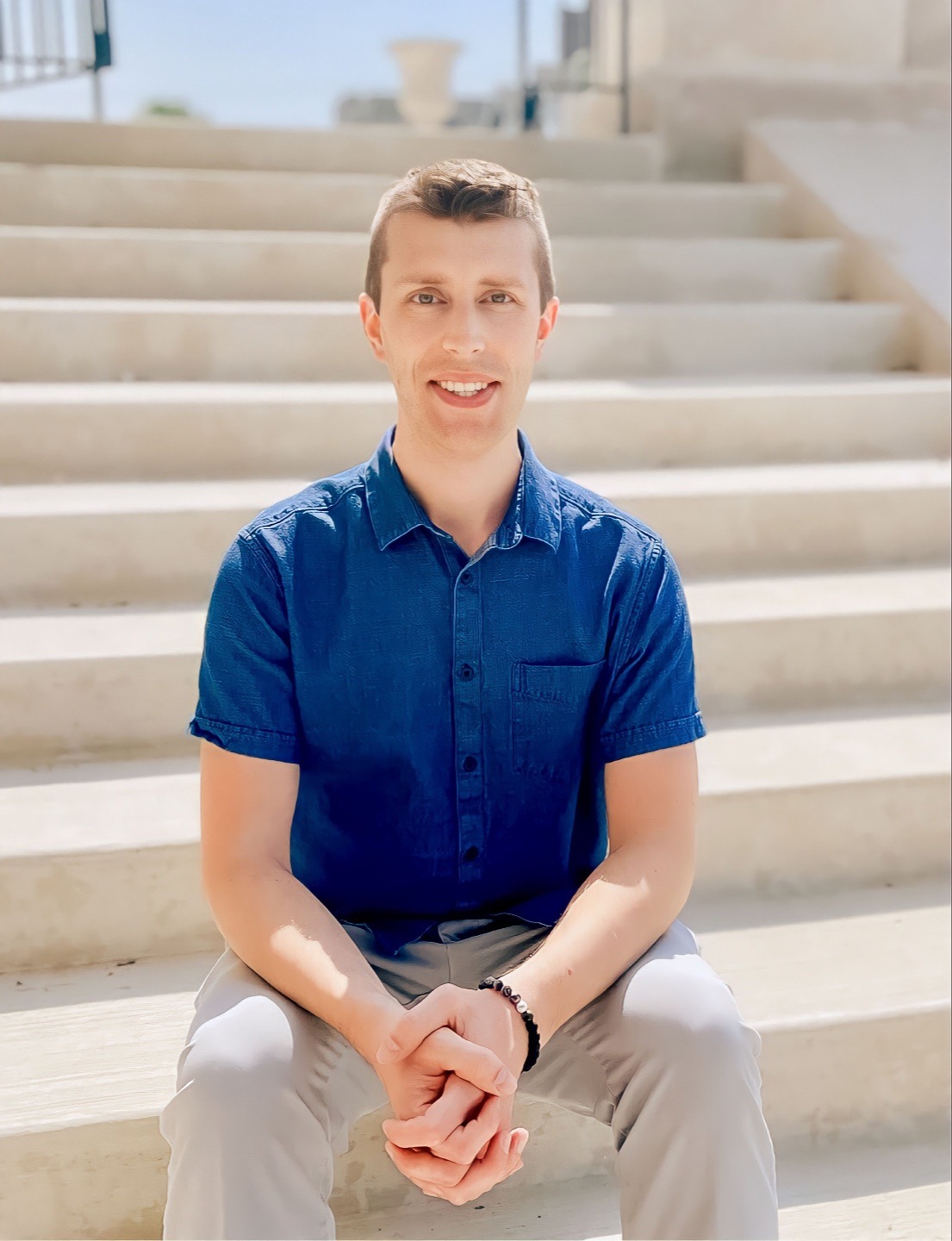 Zac Weikal sitting on stone steps in a blue shirt